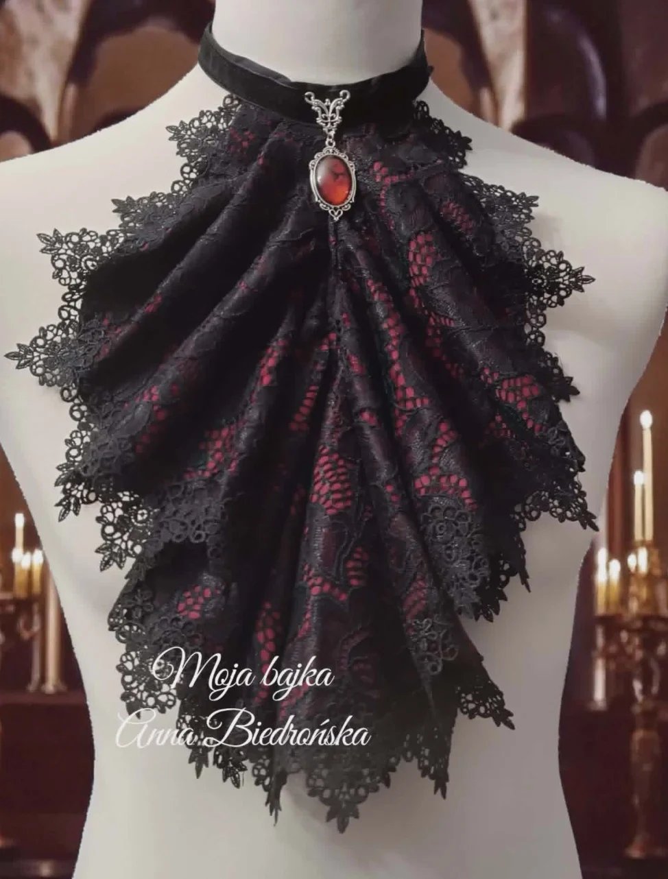 Black and burgundy lace brooch with red gemstone centerpiece displayed on mannequin