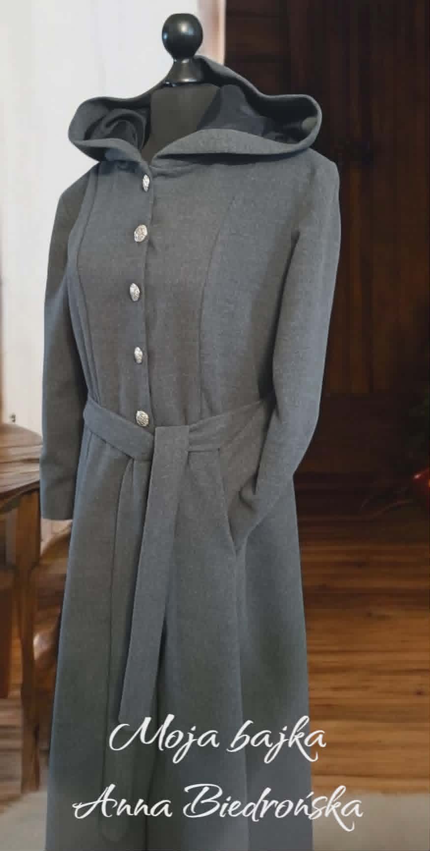Gray wool hooded coat on a dress form with silver buttons and belt, displayed indoors