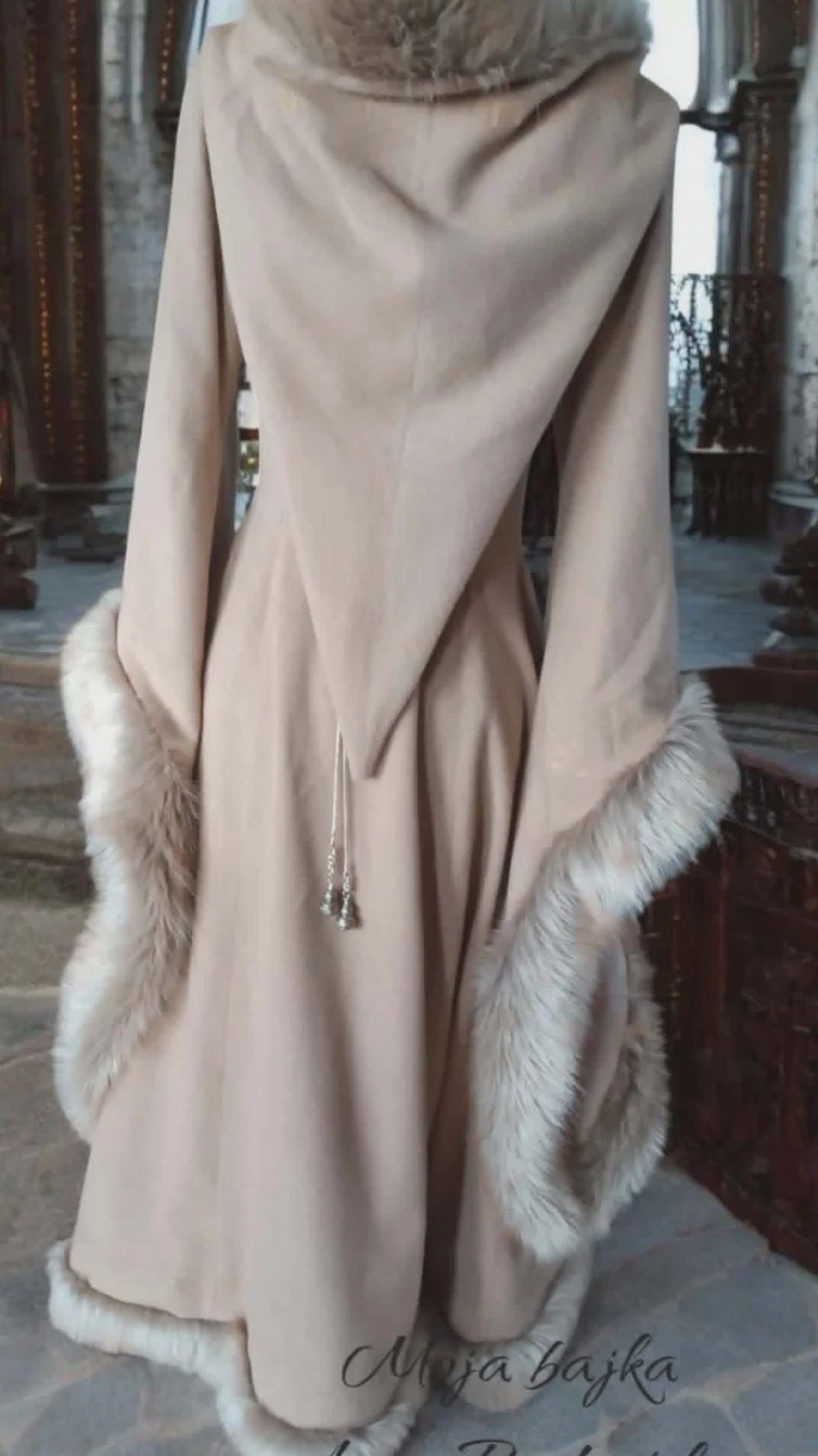 Beige wrap or shawl with white fur trim displayed on a dress form in an elegant indoor setting