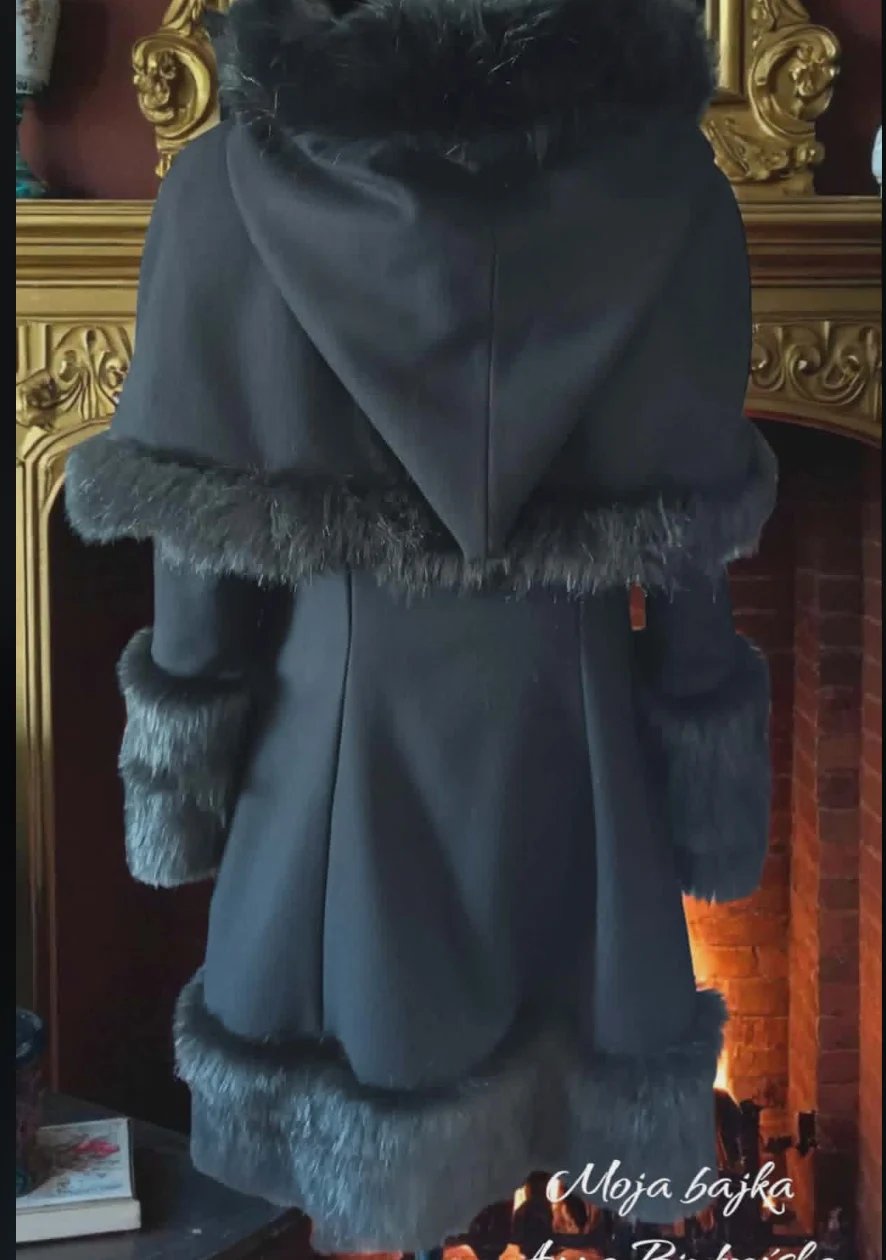 Black wool coat with fur collar and cuffs displayed on ornate gold-trimmed mirror or frame