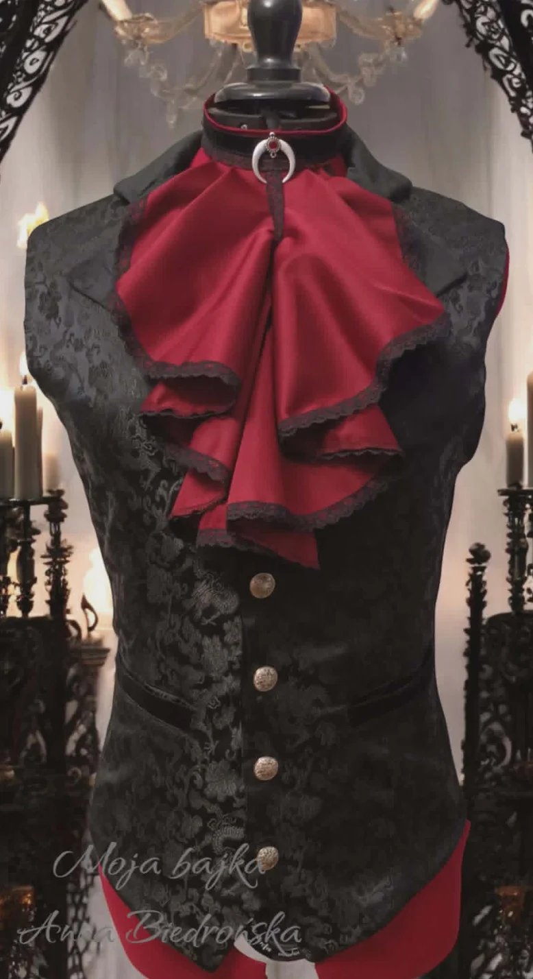 Black velvet sleeveless corset with red ruffled collar and trim, displayed on dress form with ornate candelabras