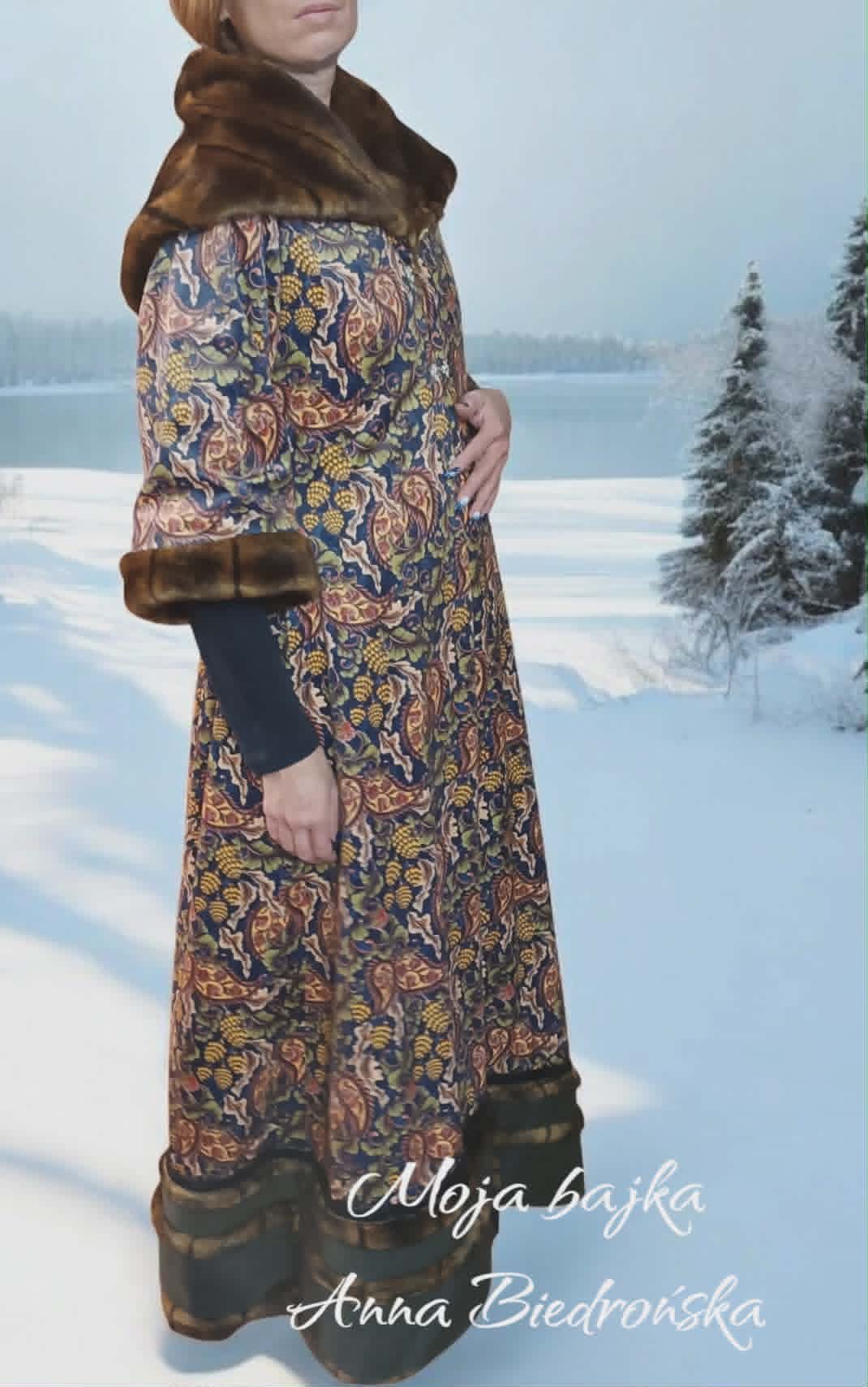 Woman in ornate traditional dress with fur stole standing in snowy landscape with frozen lake