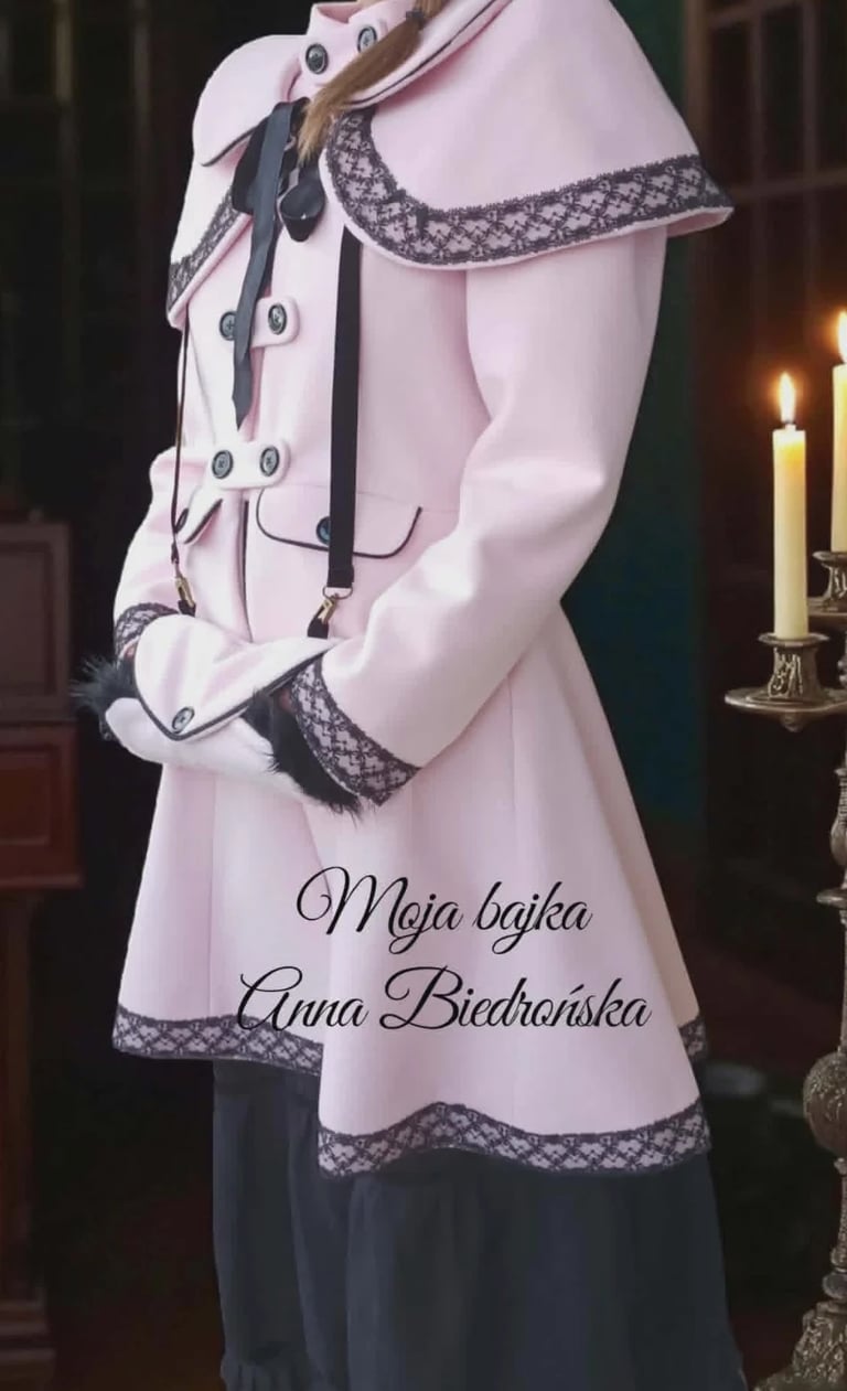 Pink and black traditional dress on mannequin with lace trim and decorative cord, displayed indoors with candles nearby