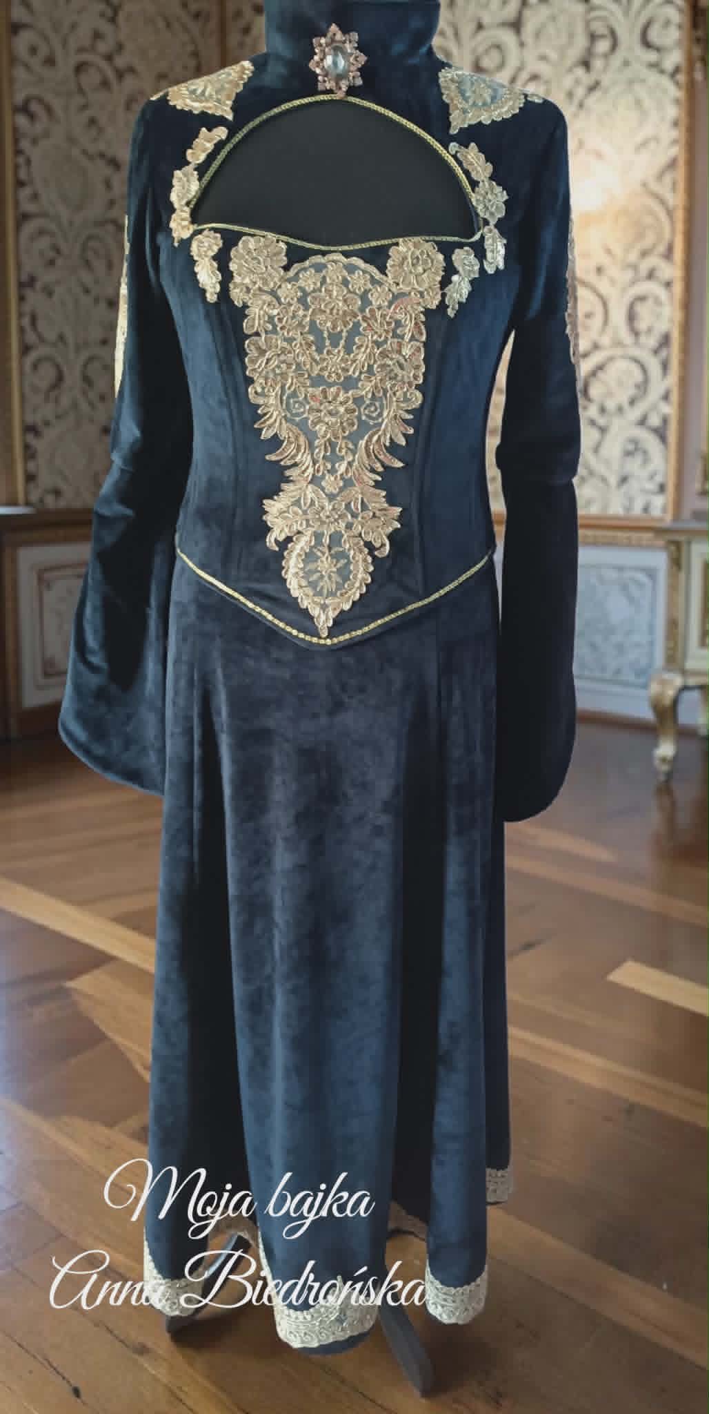 Navy blue velvet historical gown with ornate gold embroidered details and decorative shoulder pieces displayed on mannequin