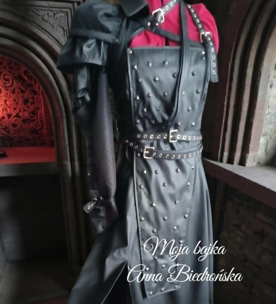 Black studded leather dress displayed on mannequin with hot pink fabric detail and decorative belt
