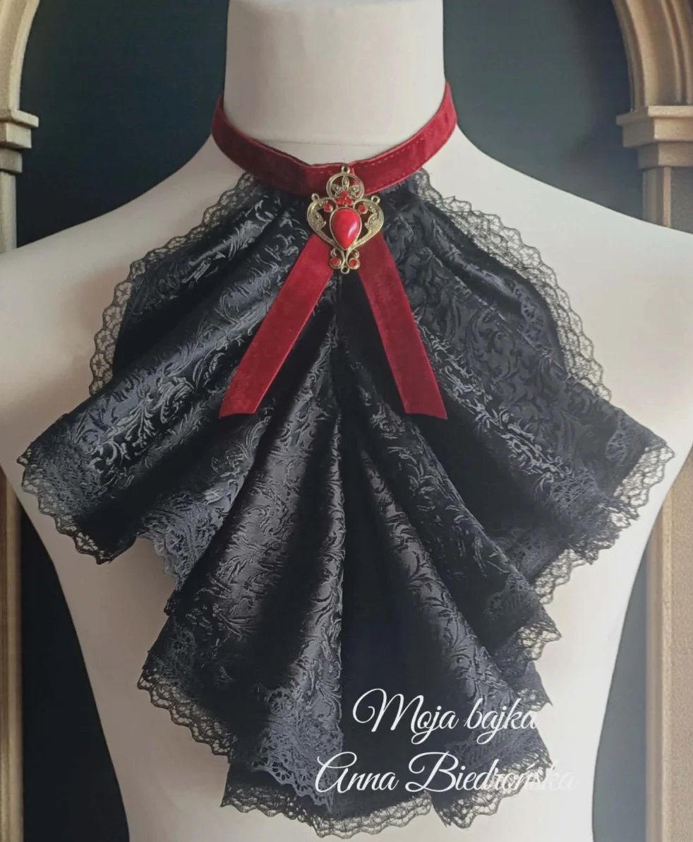 Black lace bow brooch with red ribbon on mannequin bust, featuring ornate gold centerpiece charm