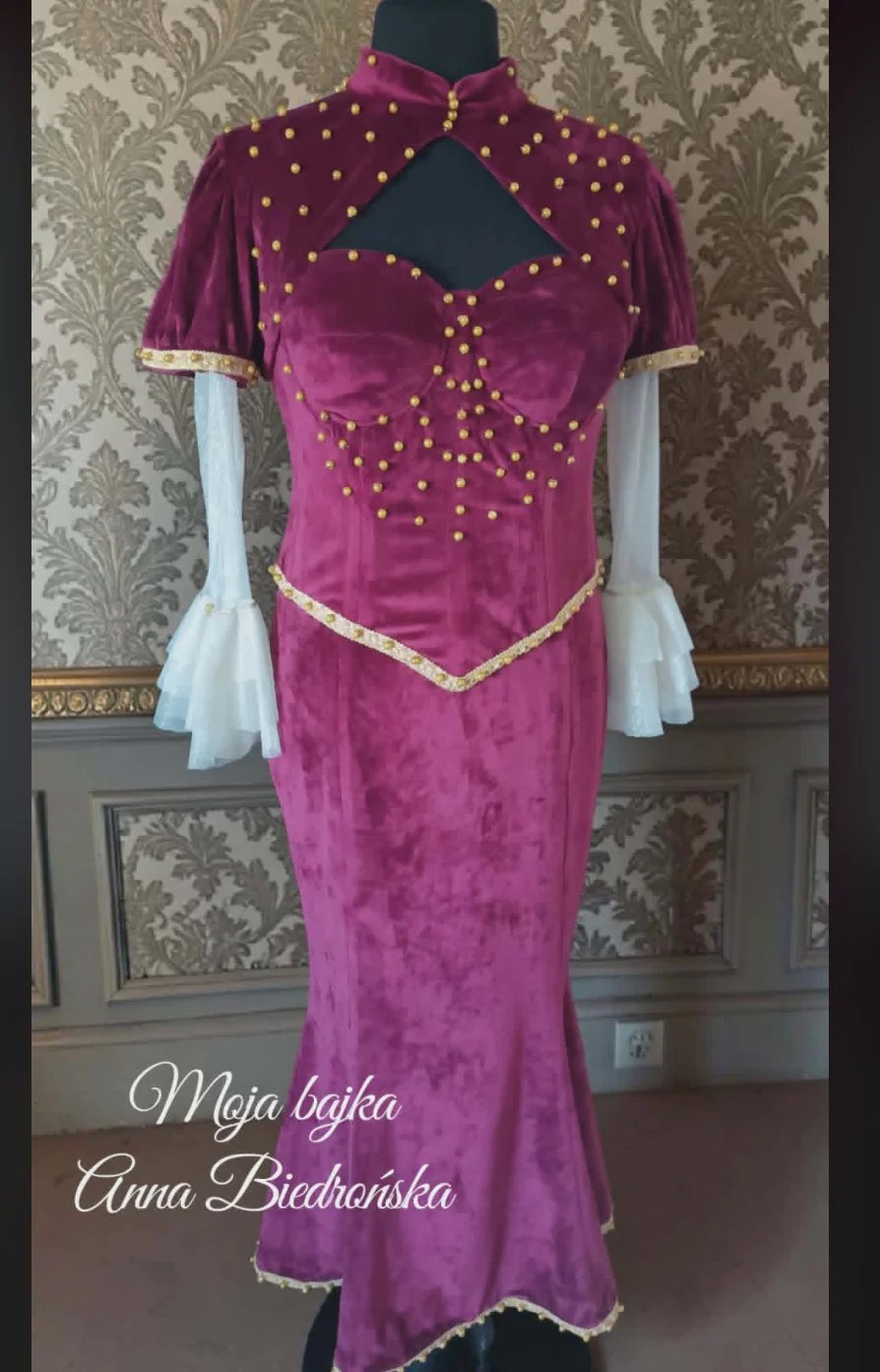 Purple velvet dress with gold beaded detailing on mannequin against ornate wallpapered background