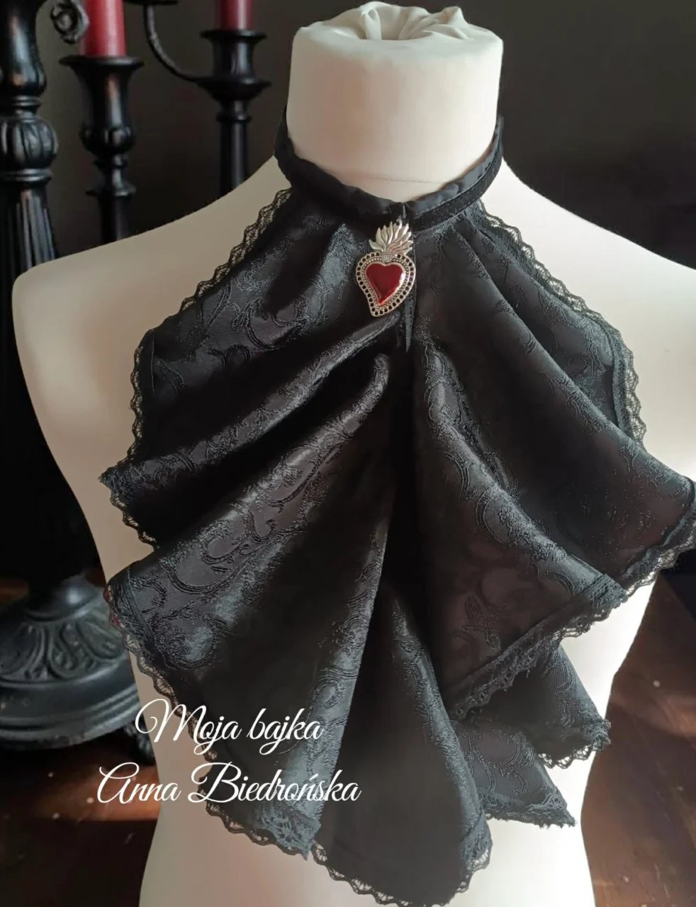 Black lace choker with red heart pendant on a dress form, styled as a gothic necklace accessory