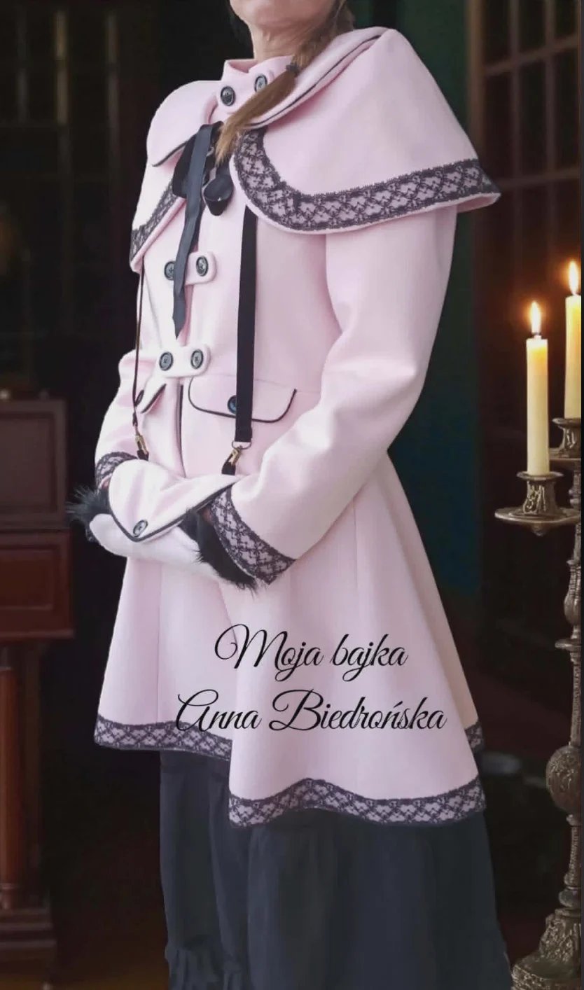 Woman wearing a pink and white traditional Polish costume with lace trim and decorative vest, standing by candlelight