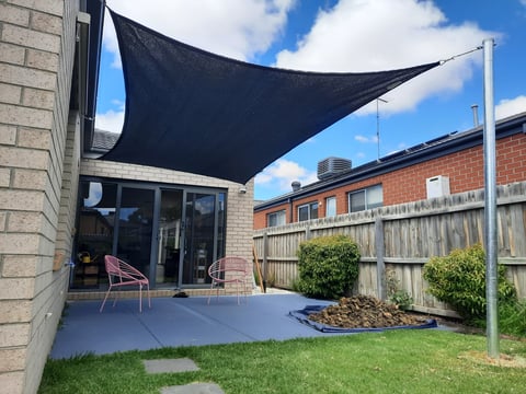 Modern backyard transformation by Home and Asset Management - black shade sail over gray decking, landscaped garden beds and timber fencing in Geelong