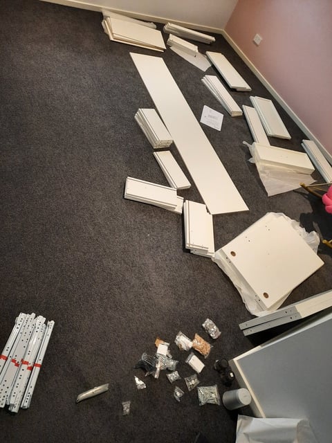 Flat pack furniture assembly in progress - pieces and hardware laid out on carpet, Geelong handyman at work