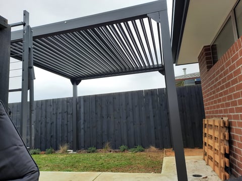 Adjustable louver pergola installed by Geelong handyman in residential backyard with dark fencing and brick wall