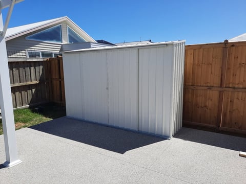 White metal gable-roof storage shed assembled and attached to house exterior by Home and Asset Management in Geelong