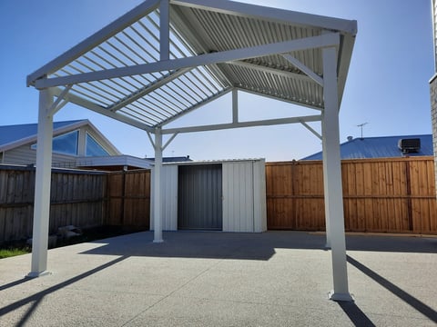 Modern white pergola with metal roof and corrugated wall panels in residential backyard setting