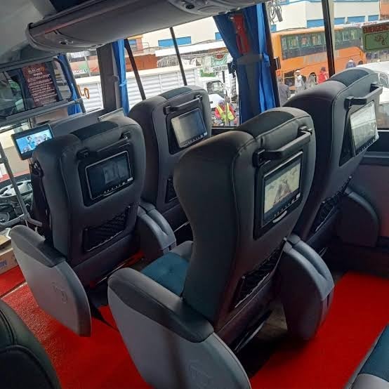 Interior of a Modern Coast tour bus with rows of black seats and individual headrest screens