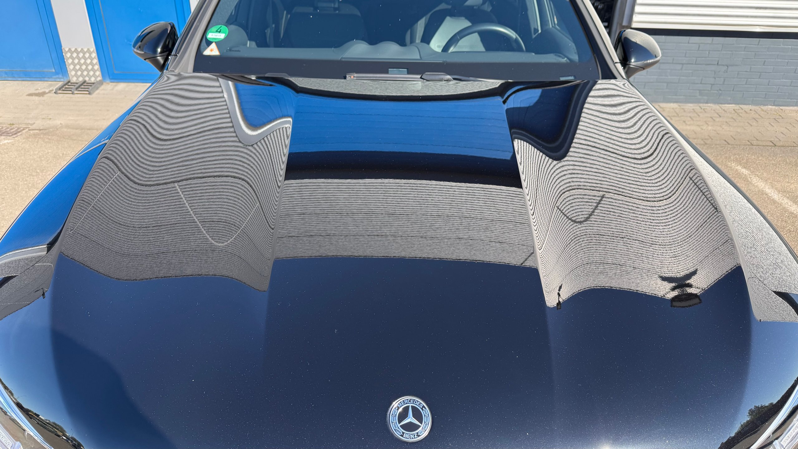 Na: Blue Mercedes-Benz car viewed from above showing hood with wave pattern design and front windshield