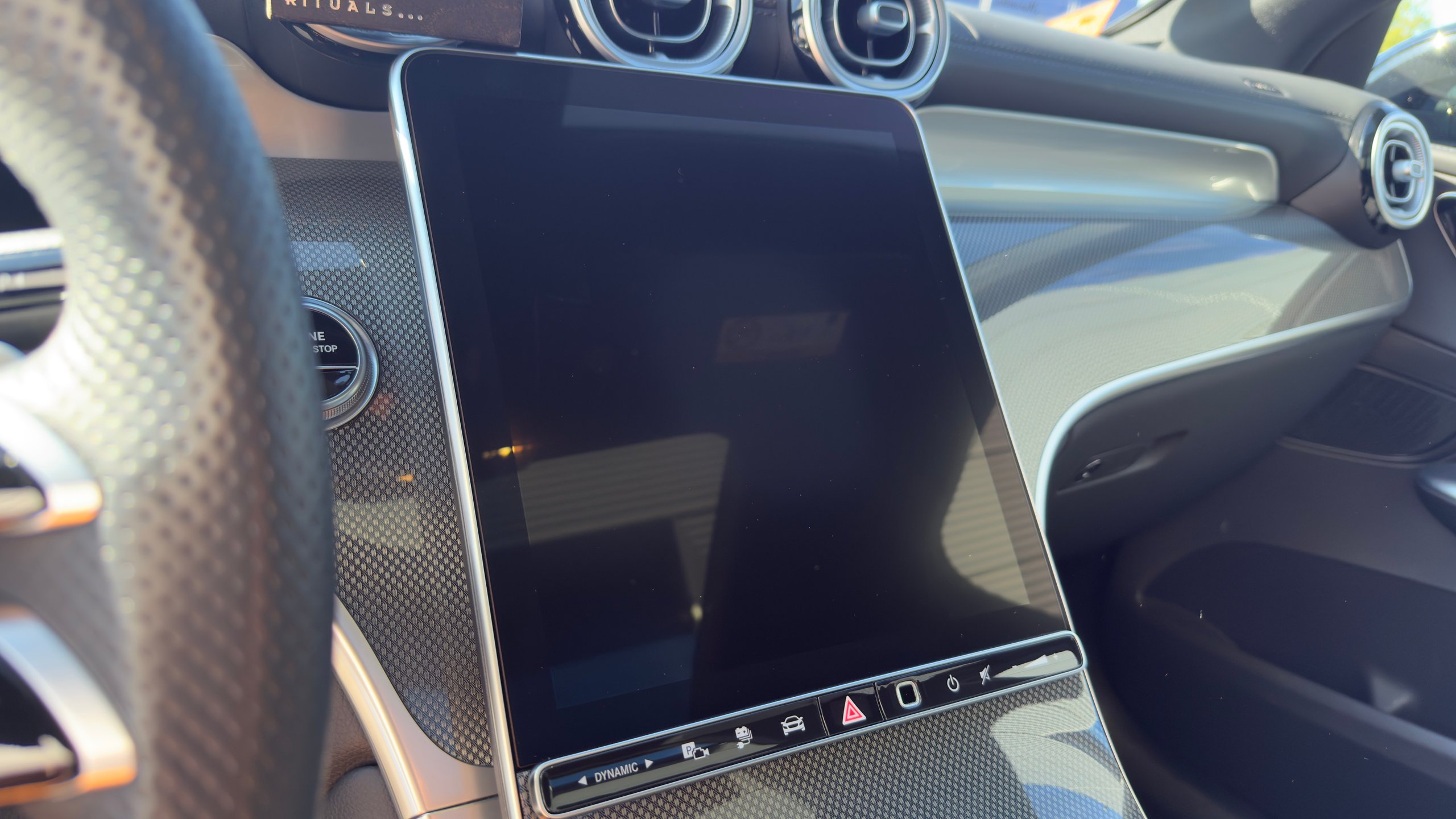 Na: Car interior dashboard showing touchscreen display and steering wheel with part of instrument cluster visible