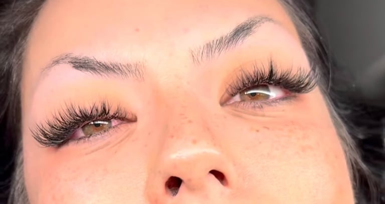 Close-up of a womans face showing dramatic black false eyelashes and defined eyebrows with natural skin makeup