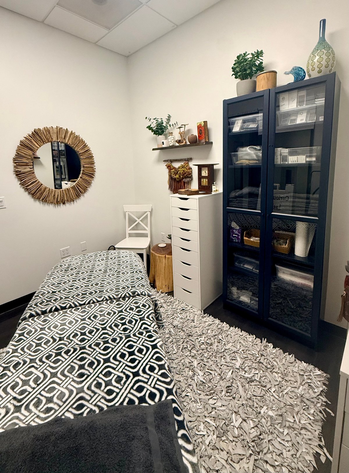 Cozy studio with geometric patterned rug, white chair, and woven mirror