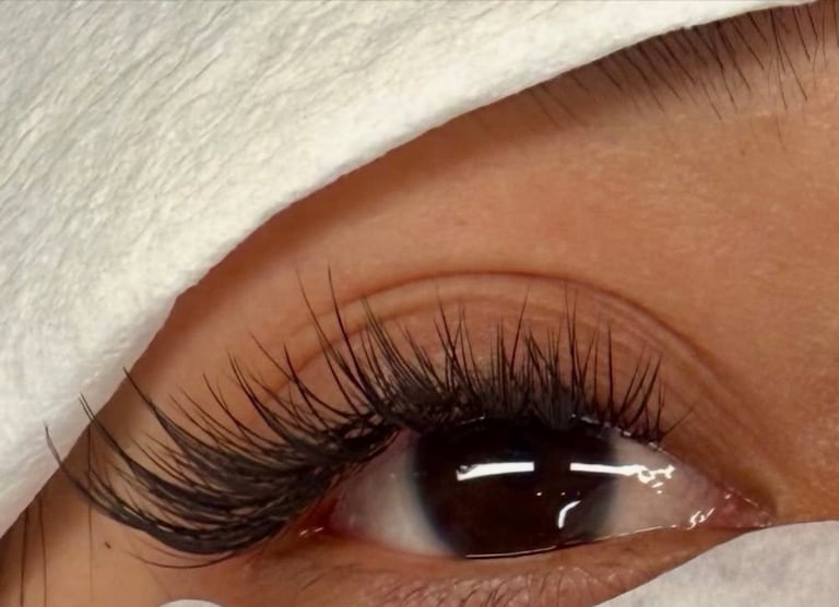 Close-up of long black lash extensions framed by a white headwrap