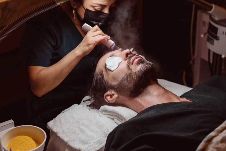 Barber applying shaving cream to a bearded mans face during grooming service in salon