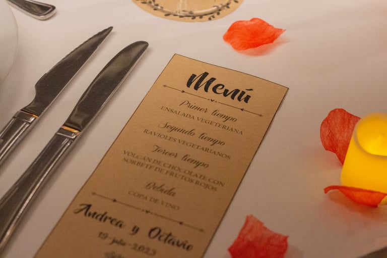 Menu card on formal place setting with silverware, scattered rose petals, and decorative elements