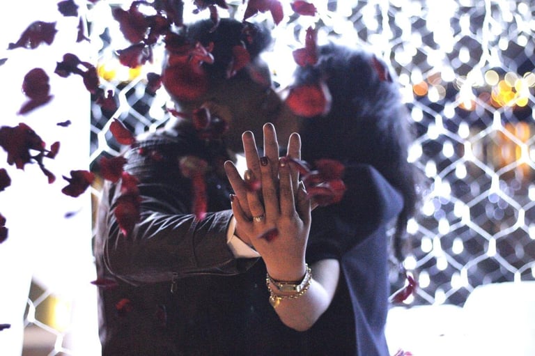 Person with hand raised to camera amid colorful confetti and geometric patterned background