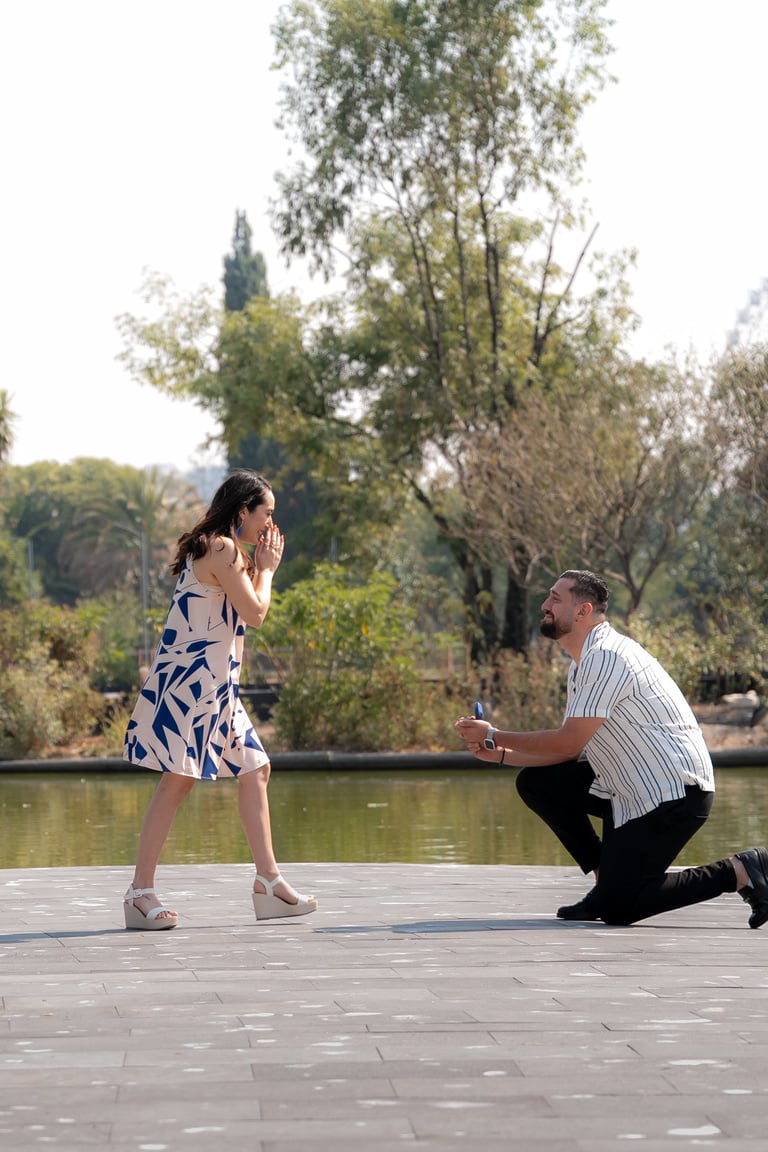 Man proposing to woman on a waterside deck with trees and calm water in background