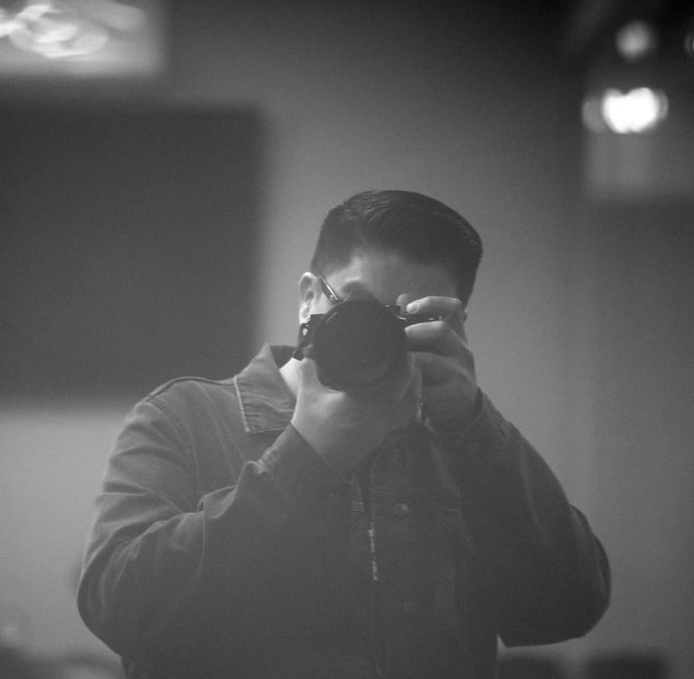 Black and white photograph of a person holding a camera up to their face, preparing to take a photo
