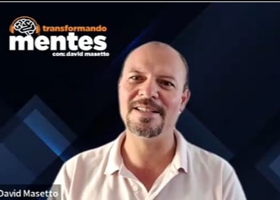 David Masetto smiling at camera wearing white shirt with Transformando Mentes logo and blue geometric design in background