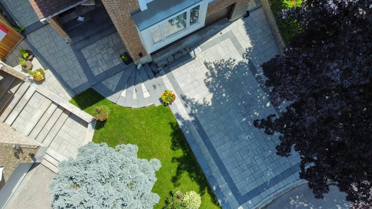 Overhead view of modern residential courtyard with green lawn, paved walkway, building entrance, and landscaped areas