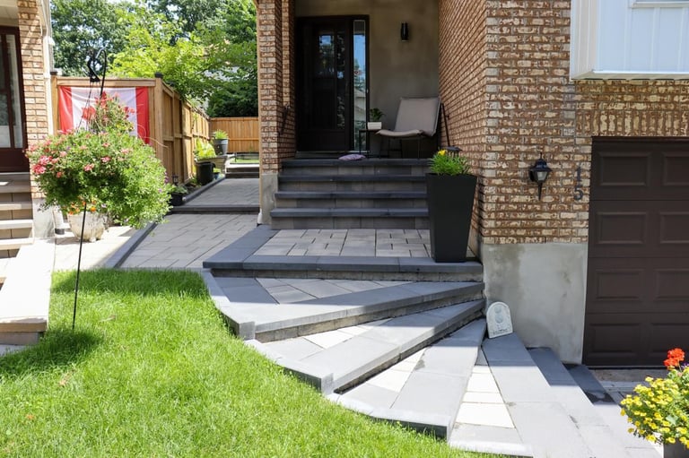 Modern brick house exterior with curved stone patio steps, green lawn, potted plants, and garage entrance