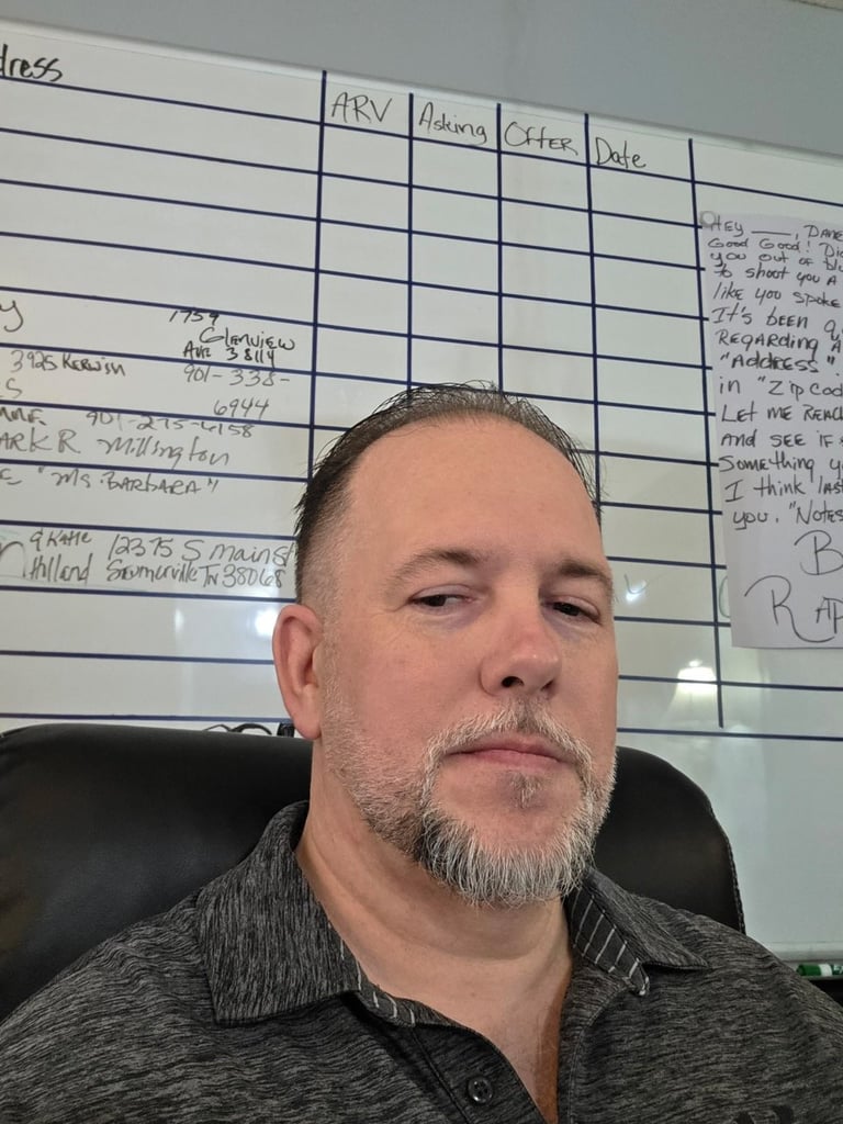 Dane, Roofing Specialist at North Slope Exteriors, in the office in front of a property tracking whiteboard