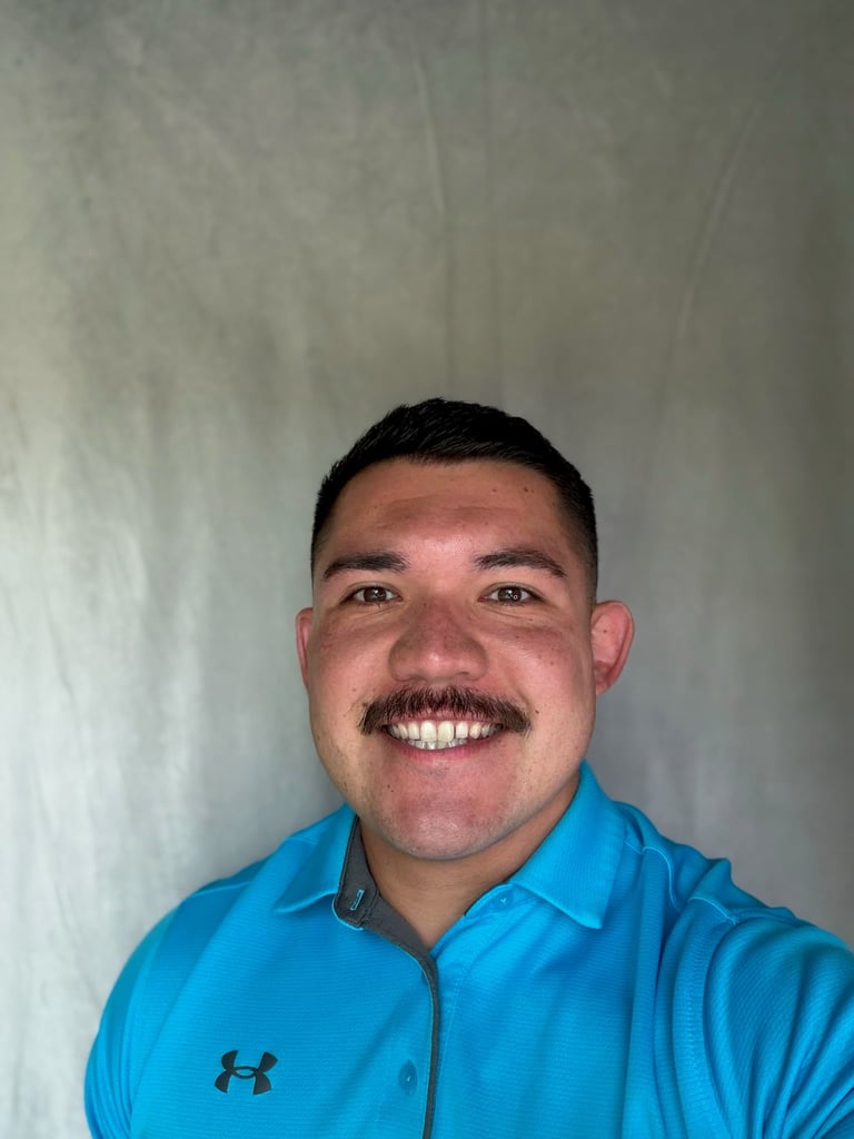 CJ, Project Manager at North Slope Exteriors, smiling in a bright blue Under Armour polo against a neutral background