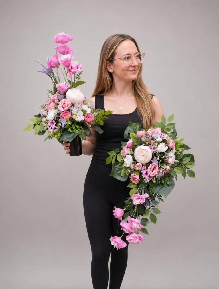 Woman in black dress holding two large floral arrangements with pink roses and white flowers against a neutral background