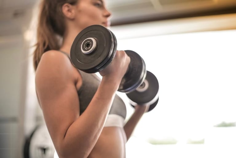 Woman performing a bicep curl with two black dumbbells during a workout indoors