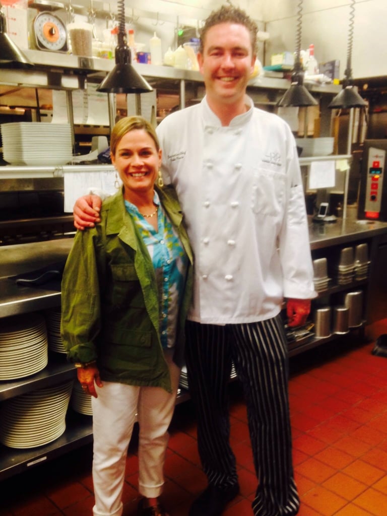 Chef Jake in white coat and striped pants standing with a young girl in a professional kitchen