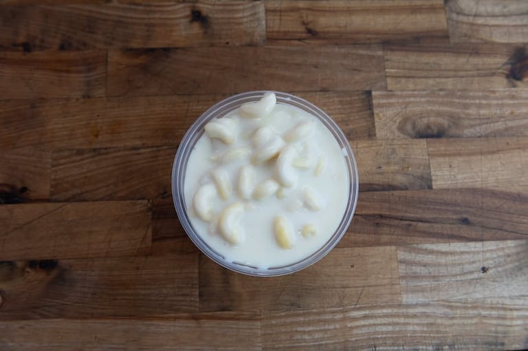 Mac and cheese in a clear cup, creamy with elbow pasta on a wooden surface