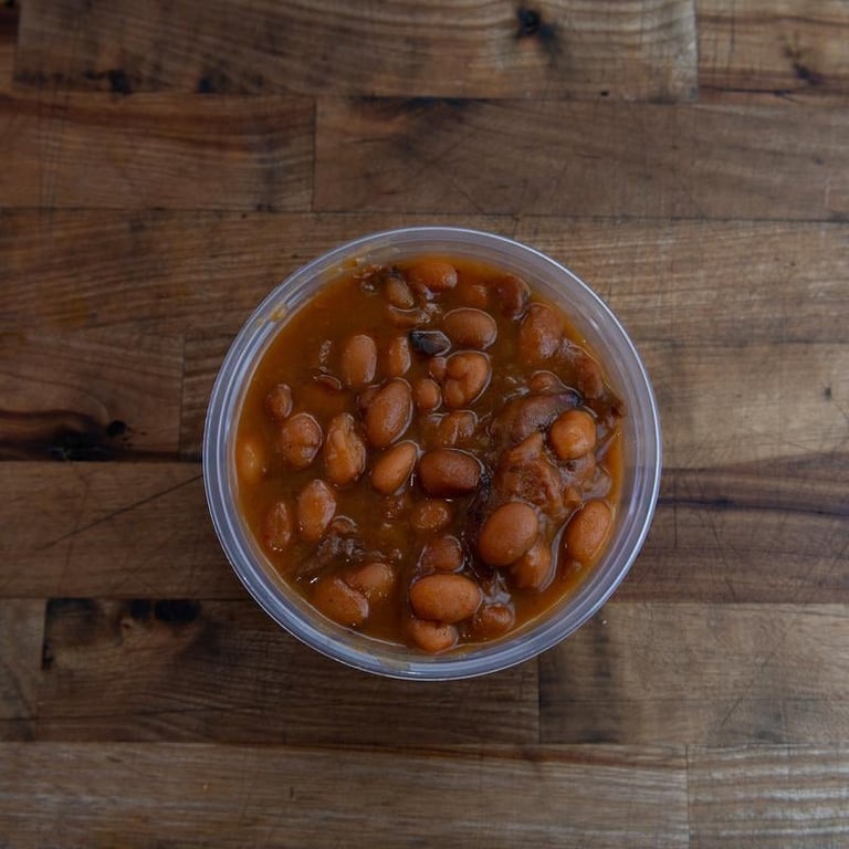 Clear bowl of baked beans in tomato sauce on a wooden surface
