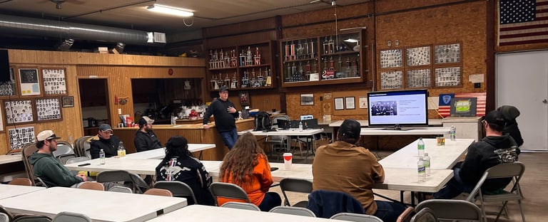 Students sitting at desks in a classroom with wood paneling, bulletin boards, and an American flag on the wall.