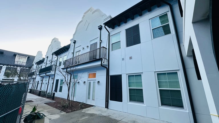 Modern white residential apartment buildings with balconies and large windows on a paved street