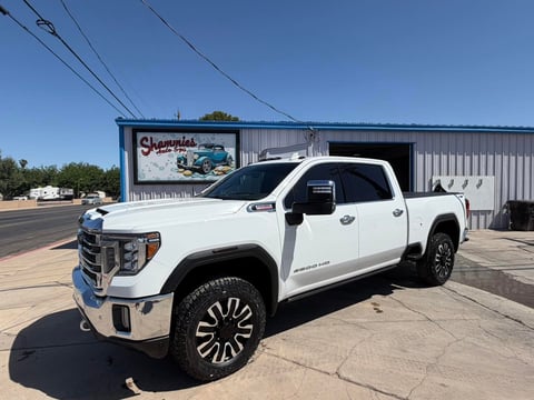 White GMC Sierra pickup truck parked in front of a metal building with power lines overhead
