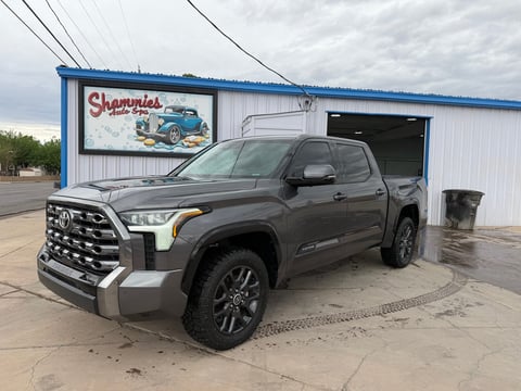 A gray Toyota pickup truck parked outside Shammies auto shop with blue and white exterior