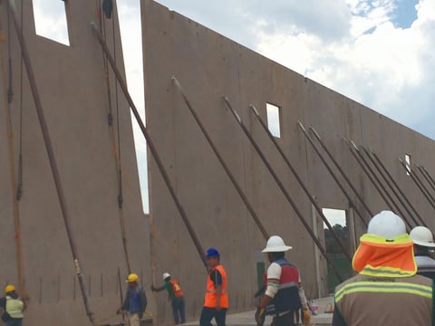 Muro de concreto Tilt-Up con soportes diagonales y trabajadores con casco en obra