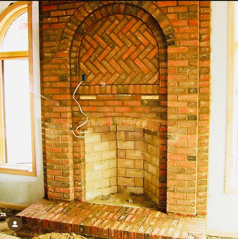 Empty brick fireplace with arched opening and herringbone brick pattern