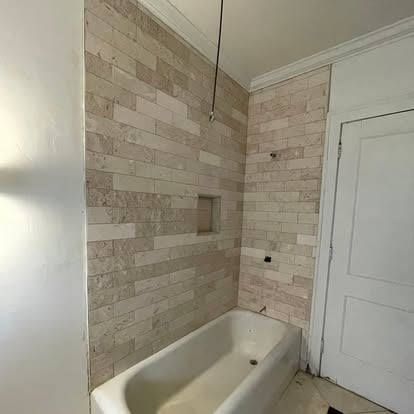 Newly tiled bathroom shower and tub area with beige subway tiles and white fixtures