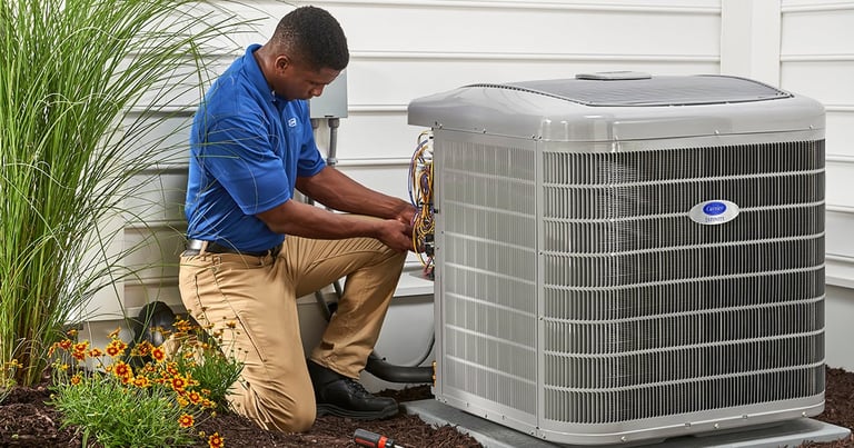 HVAC technician in blue shirt servicing an outdoor air conditioning unit at a residential home