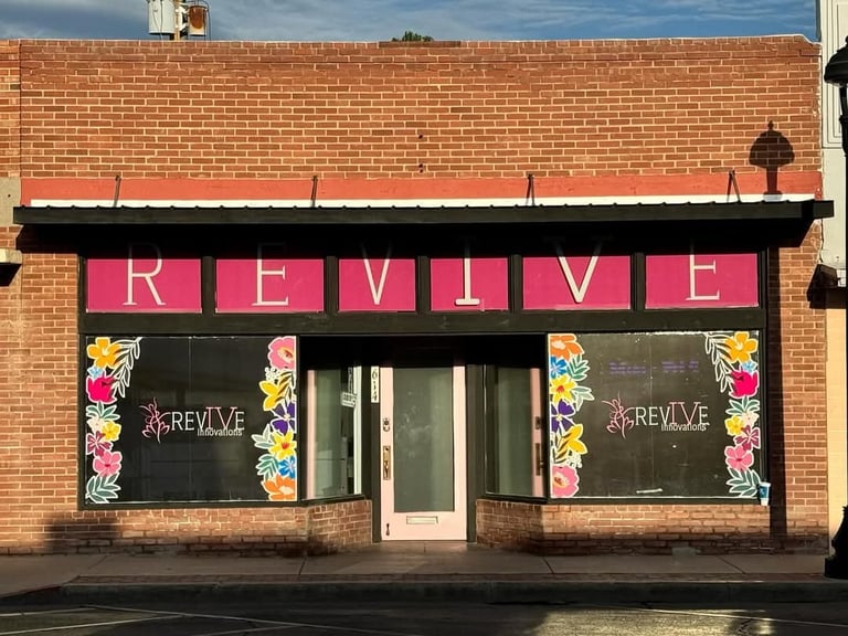 Storefront of REVIVE shop with pink signage and floral window decorations on red brick building