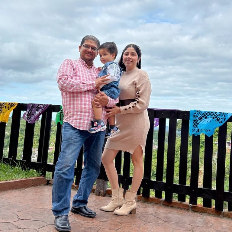Raúl Reyes con su familia — esposa e hijo pequeño — posando al aire libre en una terraza