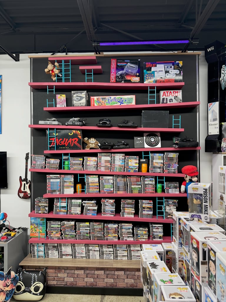 Red metal shelving unit displaying vintage video games, consoles, memorabilia, and game cases in a retro gaming collection